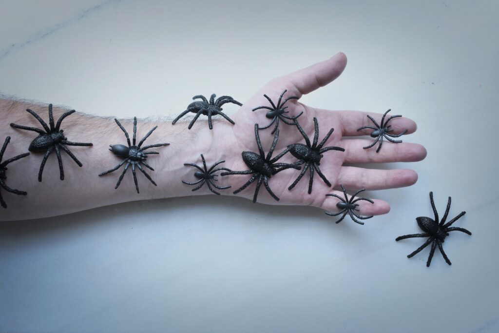 Man's arm covered with plastic spiders
